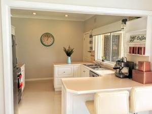 a kitchen with white cabinets and a clock on the wall at Magnolia Corner in Bowral