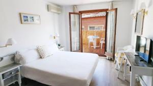 Sala de estar blanca con cama y TV en Hotel Mireia, en Lloret de Mar