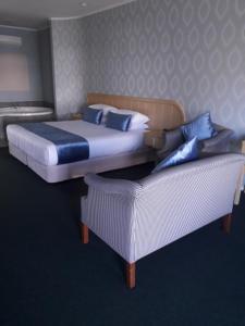 a bed and a couch in a room with a bed and a bed at Village Motel in Havelock North