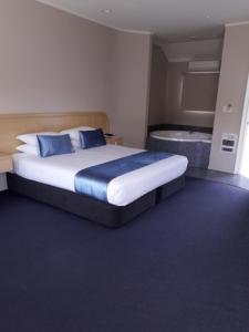 1 dormitorio con 1 cama grande y bañera en Village Motel en Havelock North