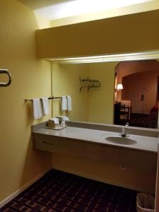Texan Inn & Suites في هيوستن: حمام مع حوض ومرآة كبيرة