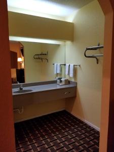 Texan Inn & Suites في هيوستن: حمام مع حوض ومرآة