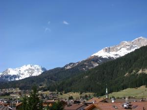 a town with snow capped mountains in the background at Hotel Nès Crépes in Pozza di Fassa