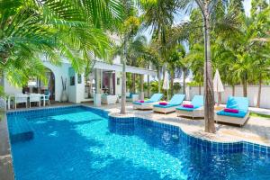 a swimming pool with palm trees and blue lounge chairs at Villa Tropicale in Rawai Beach
