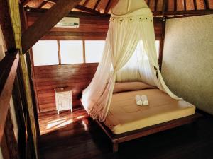 a bed in a room with a mosquito net at Rhipidura Bungalows by Phocéa in Pemuteran