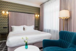 Habitación de hotel con cama y silla azul en Altay Hotel, en Barnaul