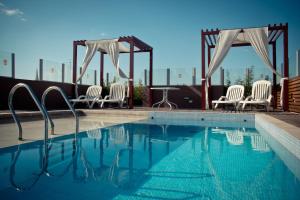 a swimming pool with chairs and a gazebo at Del Fundador in Córdoba