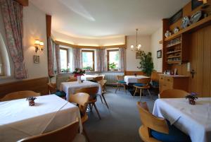 a dining room with tables and chairs and windows at Ferienwohnung Pension Tirol in Bichlbach