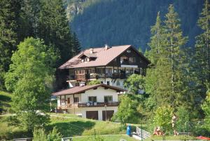 une grande maison au sommet d'une colline avec des arbres dans l'établissement Ferienwohnung Pension Tirol, à Bichlbach