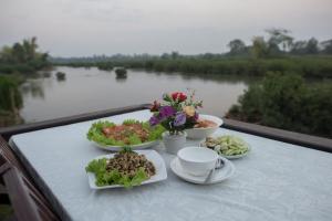 Ban Khon的住宿－Chanhthida Riverside Guesthouse and The River Front Restaurant，河上阳台的餐桌,上面有盘子