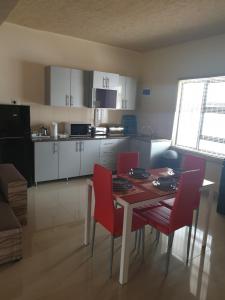 een keuken met een tafel en rode stoelen in een kamer bij MATAT GARDENS in Matatiele