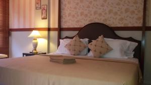 ein Schlafzimmer mit einem Bett mit weißen Laken und Kissen in der Unterkunft Genting Sempah Berjaya Hill Cottage in Bukittinggi