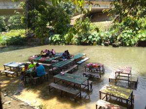 Un groupe de personnes assises à des tables dans une rivière dans l'établissement GERIK BANDING HOMESTAY, à Gerik