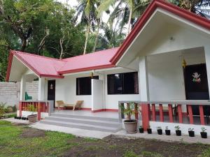 una pequeña casa con techo rojo en SJ Pabua Travellers Inn, en Mambajao