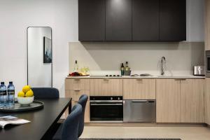 a kitchen with wooden cabinets and a table with chairs at Quest NewQuay in Melbourne