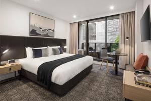 a hotel room with a large bed and a desk at Quest NewQuay in Melbourne