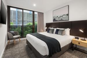 a bedroom with a large bed and a large window at Quest NewQuay in Melbourne