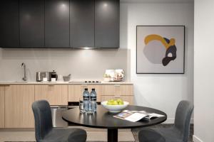 a kitchen with a black table and chairs and a counter at Quest NewQuay in Melbourne