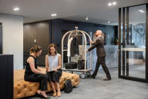 a man and two women sitting on a bed in a room at Quest NewQuay in Melbourne