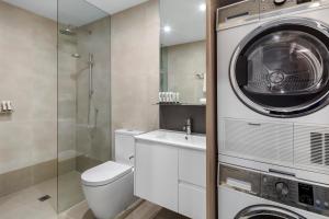 a bathroom with a toilet and a washing machine at Quest NewQuay in Melbourne
