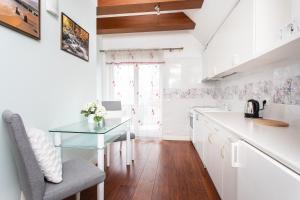 ソポトにあるroomsy guest houseの白いキャビネットとガラスのテーブル付きのキッチン