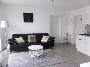 sala de estar con sofá negro y mesa en Ferienwohnung Selina-Sophie en Sehringen