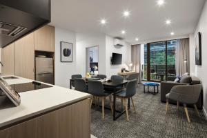 eine Küche und ein Wohnzimmer mit einem Tisch und Stühlen in der Unterkunft Quest NewQuay in Melbourne