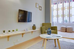 een woonkamer met een tv en 2 stoelen en een tafel bij Sweet Inn - Eixample Dreta in Barcelona