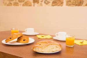 a table with two plates of bread and orange juice at Apartaments Plaça Major in Santa Pau