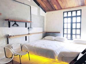 une chambre avec un lit avec deux chaises et un miroir dans l'établissement Rimba Jonker, Melaka Heritage Residance, à Malacca