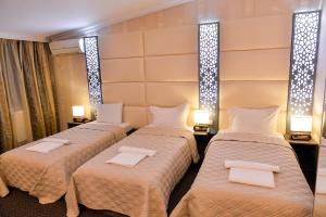 three beds in a room with lights on the wall at Hotel Old Town in Kutaisi