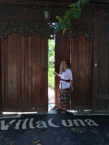 a woman standing in the doorway of a wooden door at Villa Una in Seminyak