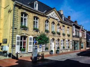 a large brick building with white shutters on a street at Skindles Guesthouse in Poperinge