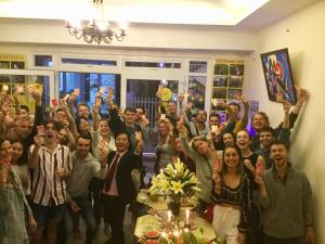 een groep mensen die poseren voor een foto met hun handen in de lucht bij Pretty Backpackers House in Da Lat