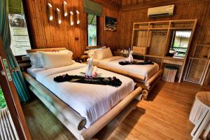 two beds in a room with wooden walls and wood floors at Phi Phi CoCo Beach Resort in Phi Phi Islands