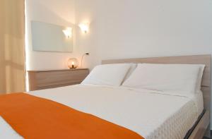 una camera con un letto bianco e una coperta arancione di Appartamento sulla spiaggia a Gallipoli