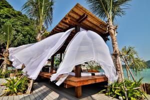 two white umbrellas on a beach with the ocean at Phi Phi CoCo Beach Resort in Phi Phi Islands