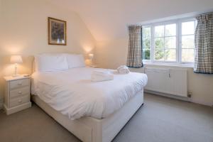 a bedroom with a large white bed and a window at 7 Whinlands in Thorpeness +7 photos