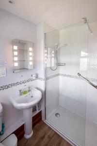a white bathroom with a sink and a shower at 7 The Uplands in Thorpeness