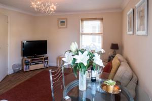 a living room with a glass table and a tv at 17 Britten Close - Aldeburgh Coastal Cottages in Aldeburgh