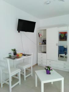 a white living room with a table and a tv at Eco in Caleta De Fuste