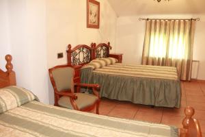 a bedroom with two beds and a chair and a window at La Alquería de Manu - venta el Laminador in Riópar
