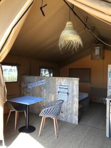 a tent with a table and chairs and a bed at Les Lodges Saint Pierre in Cap d'Agde