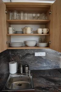 a kitchen sink with plates and dishes on a shelf at Apartma FARA in Loučná nad Desnou