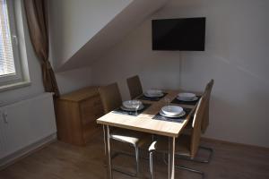 a dining room table with chairs and a television on the wall at Apartma FARA in Loučná nad Desnou