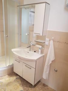een badkamer met een witte wastafel en een spiegel bij Apartman Maslov in Duće