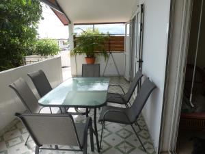 Una mesa de cristal y sillas en un balcón. en Le Miougane, en Ravine des Cabris