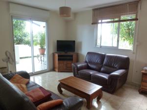 Una sala de estar con un sofá de cuero y un televisor. en Le Miougane, en Ravine des Cabris