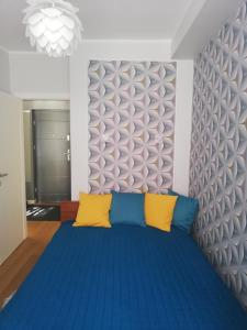 a bedroom with a blue bed with yellow pillows at Przystanek Centrum in Gdynia