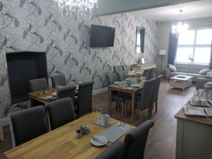 a dining room with tables and chairs and a wall at Lion House Bed & Breakfast with Restaurant in Combe Martin